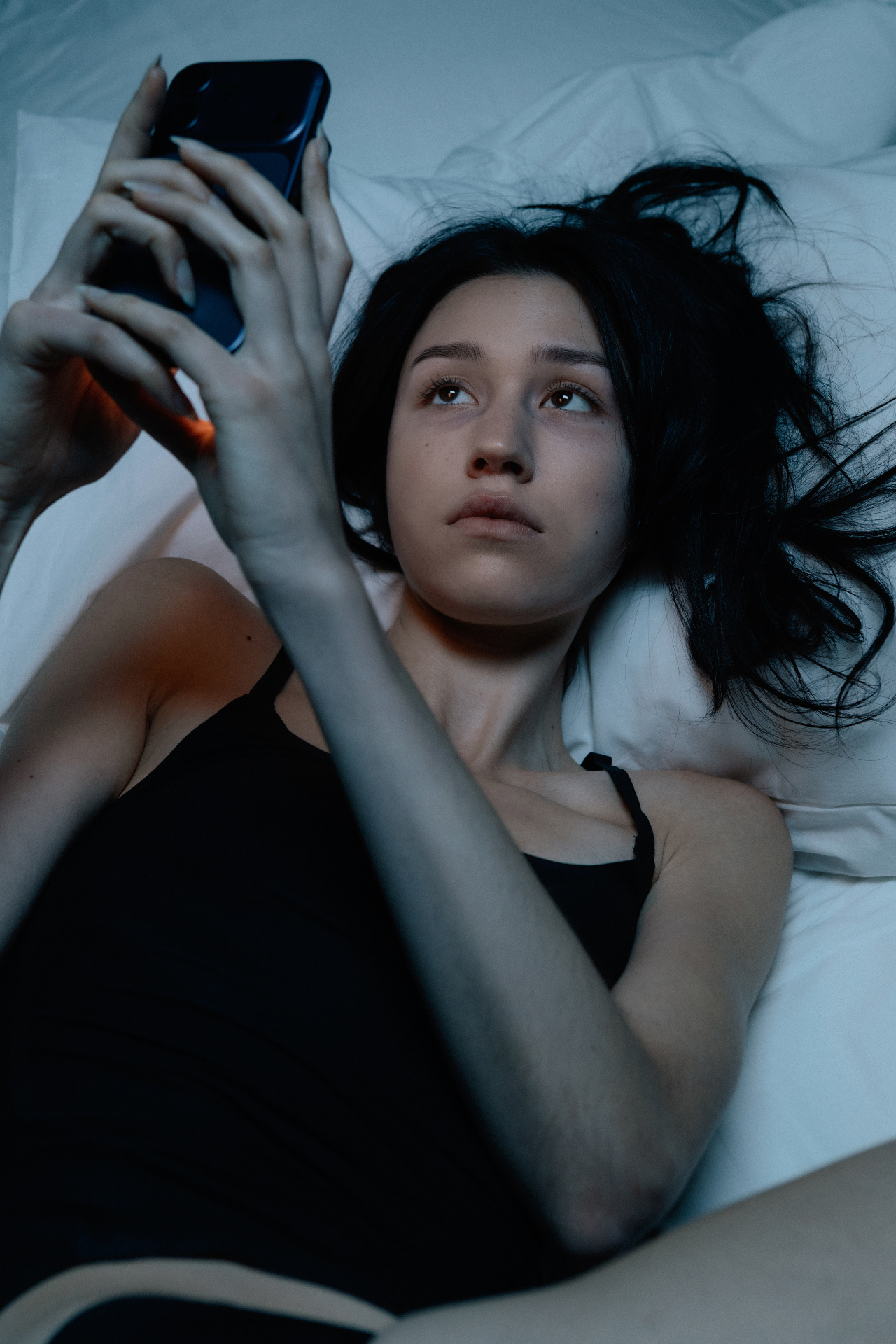 Woman lying in bed looking at a smartphone